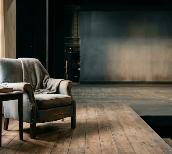 A realistic theatrical stage set depicting a lived-in domestic interior with subtle signs of inhabitation and emotional depth