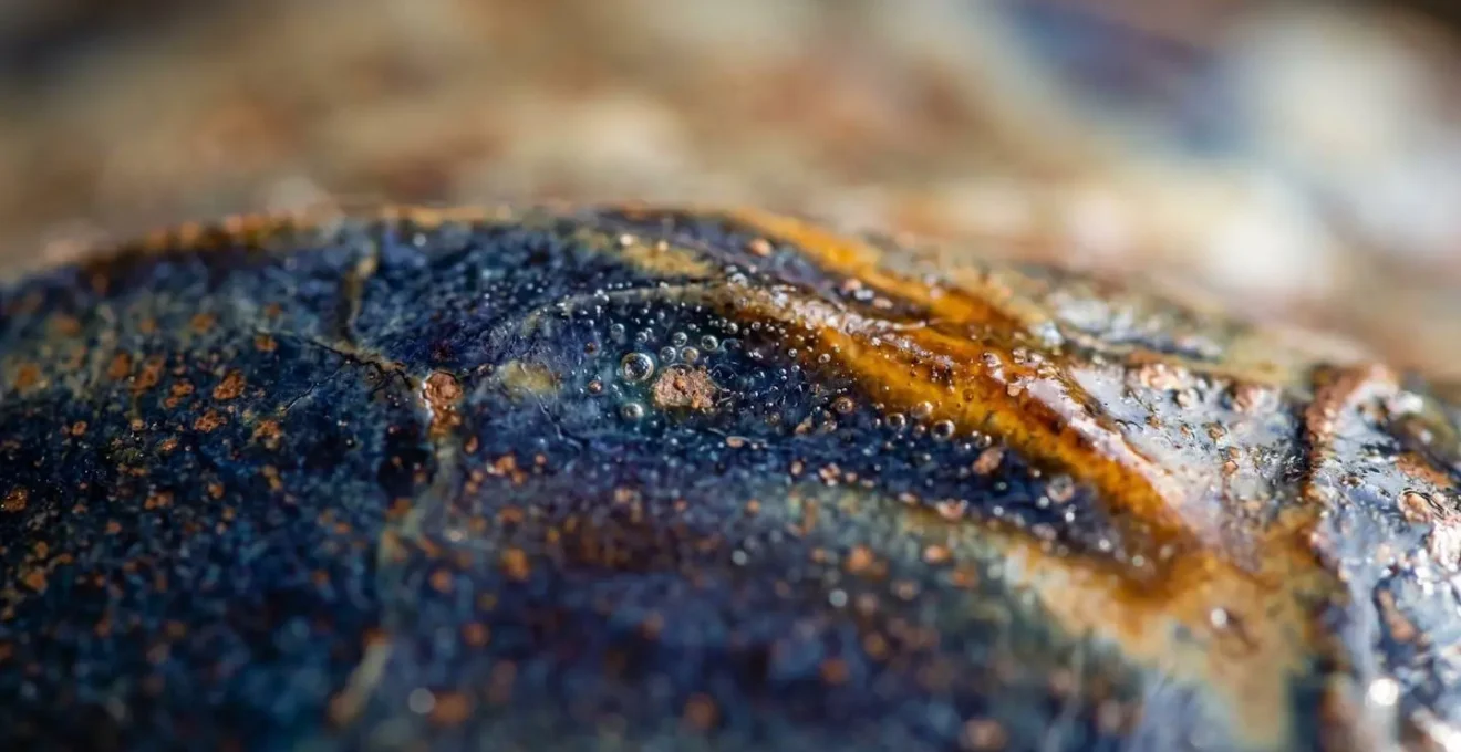 Extreme close-up macro photograph of ceramic glaze surface showing tactile texture and hand-crafted details
