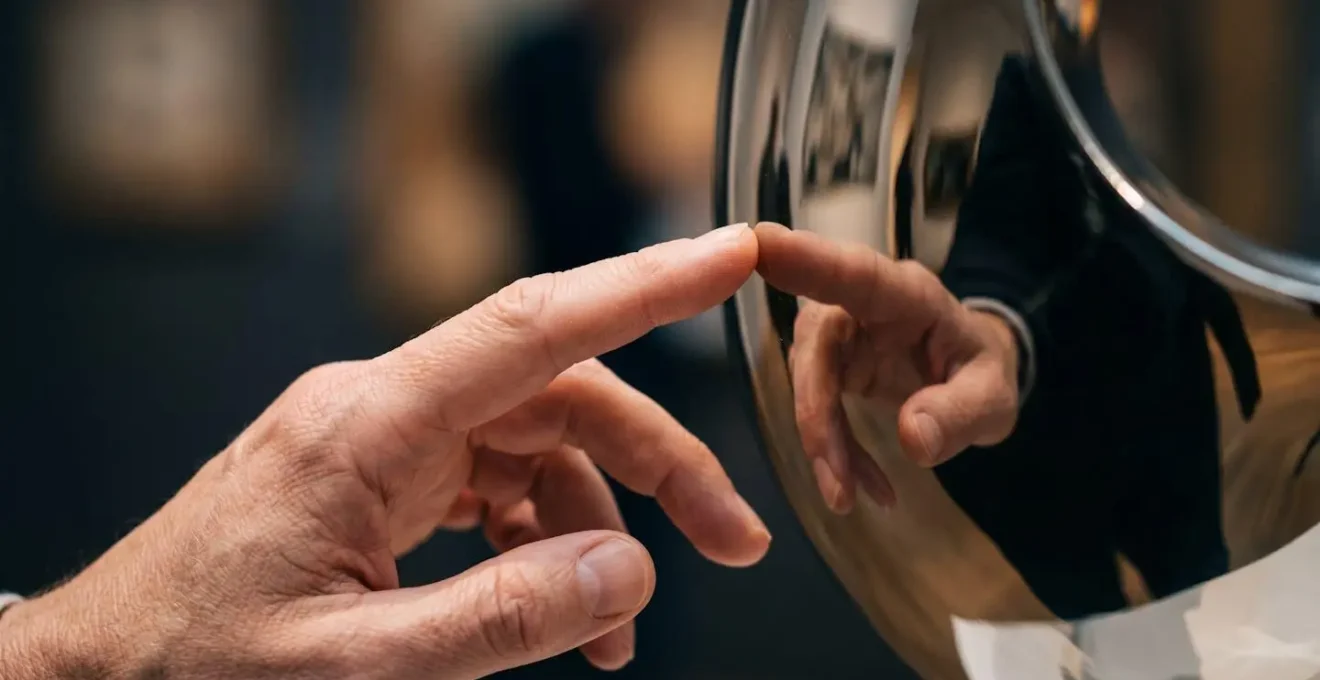 Visitor interacting with reflective interactive sculpture installation in public space